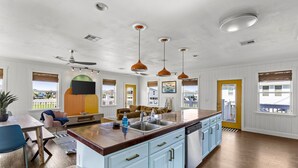 A spacious kitchen with a large island, pendant lights, and a view of the outside. - Beach Walk Retreat, Game Room & King Bed (Bolivar Peninsula)