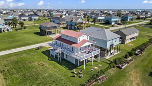 An aerial view of a residential area with houses, green lawns, and a clear sky. - Beach Walk Retreat, Game Room & King Bed (Bolivar Peninsula)