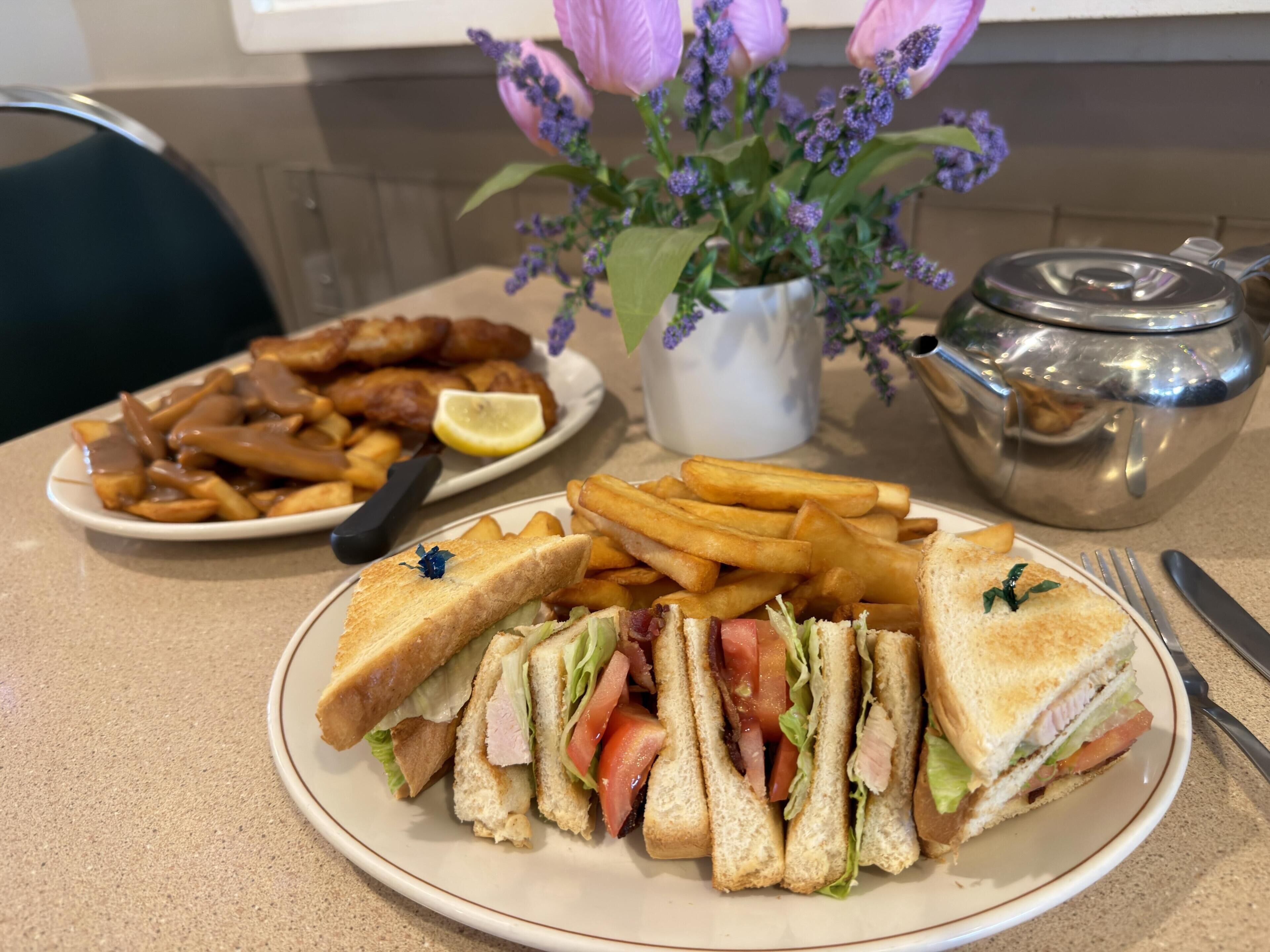 A plate of sandwiches, fries, and a small salad with a lemon wedge.
