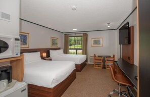 A hotel room with two beds, a desk, a chair, a TV, and a window with a view of greenery. -  Coast Whitecourt Hotel (Whitecourt)