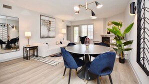 A modern dining area with a round table, blue chairs, and a chandelier. - Luxury Suite, Full Kitchen, Heated Pool (Shanty Bay)