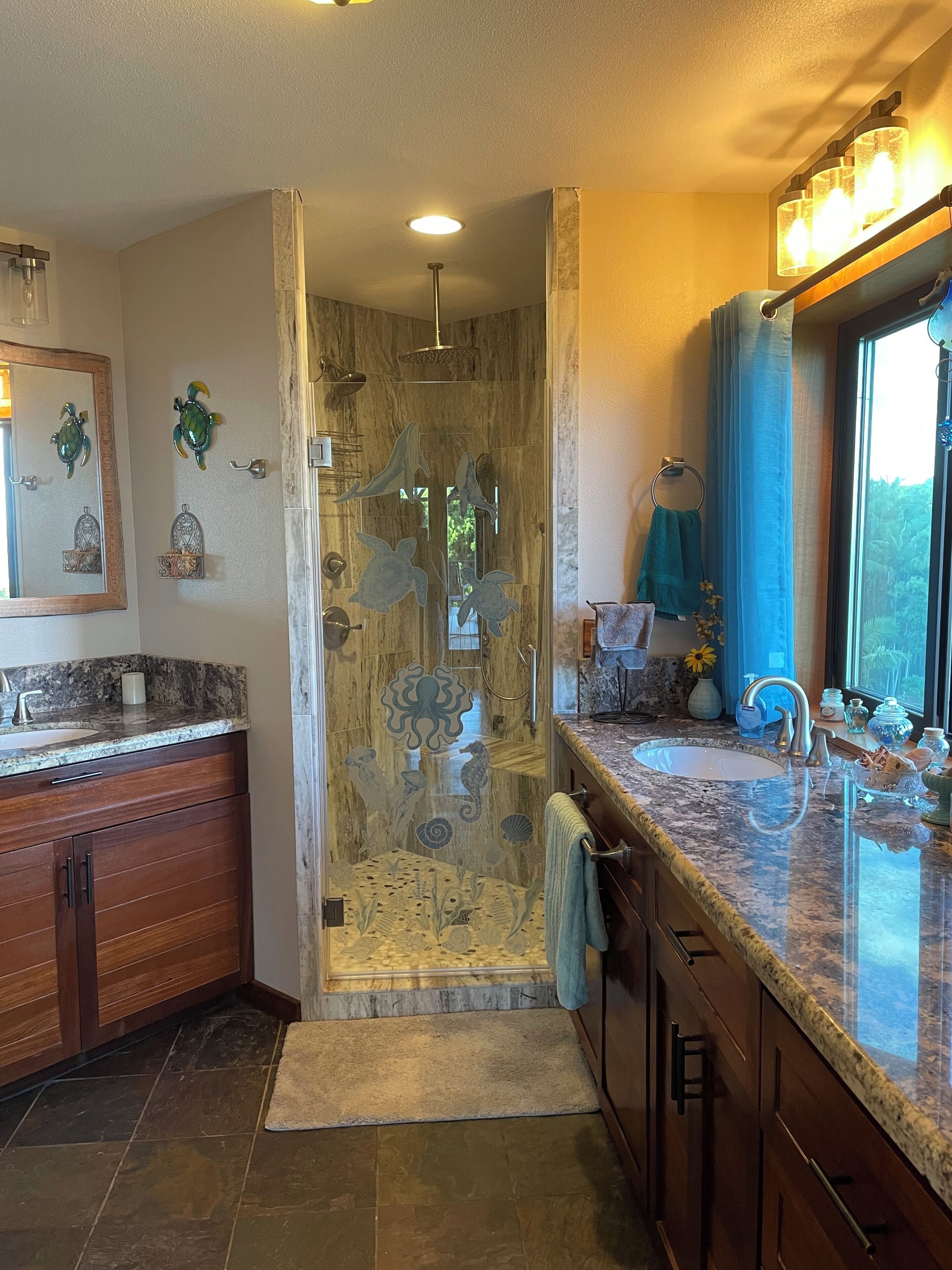 A bathroom with a glass shower enclosure, a sink, and a vanity with a mirror.