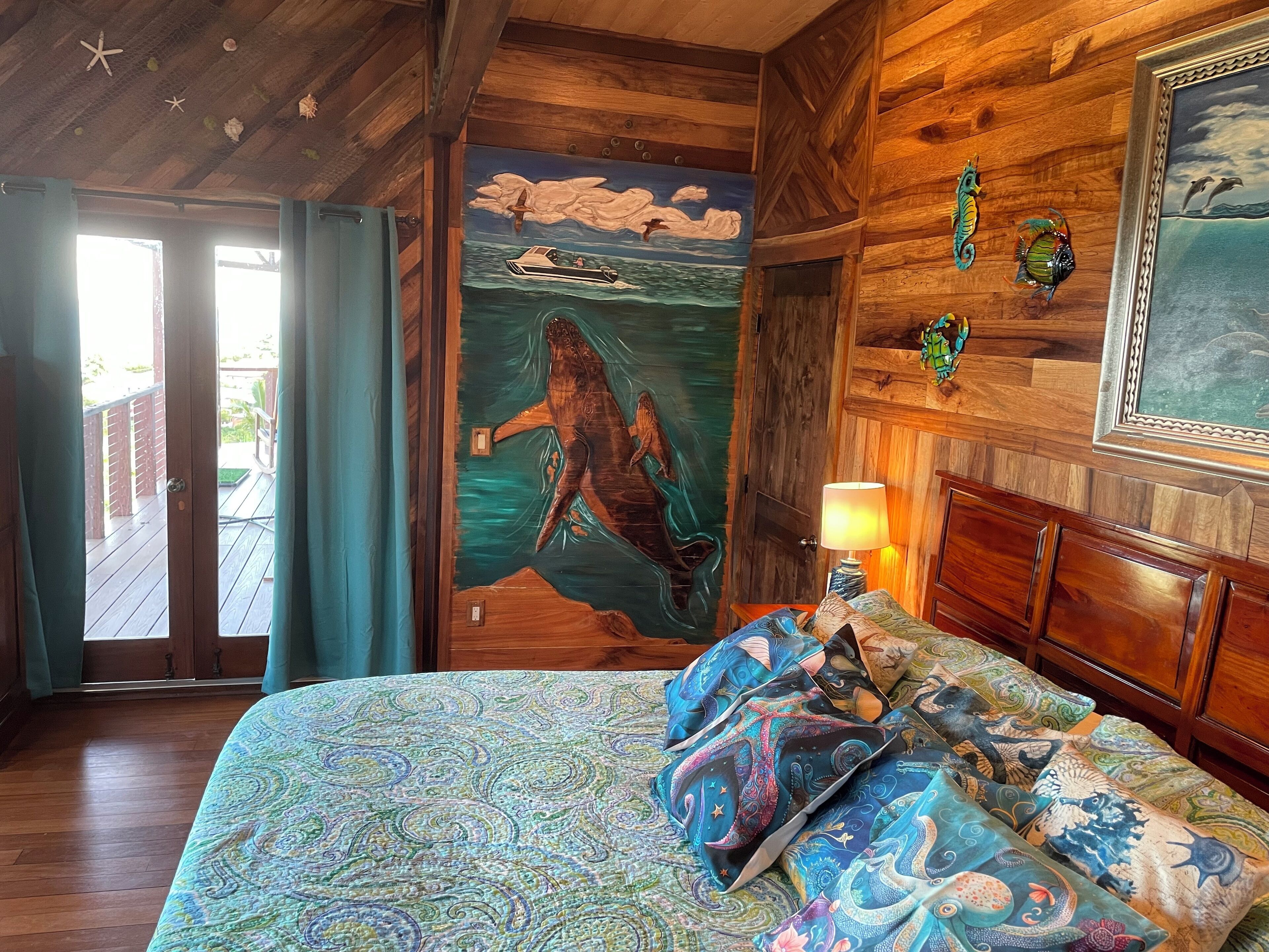 A wooden-themed room with a mural of a mermaid, a bed with patterned bedding, and a wooden headboard.