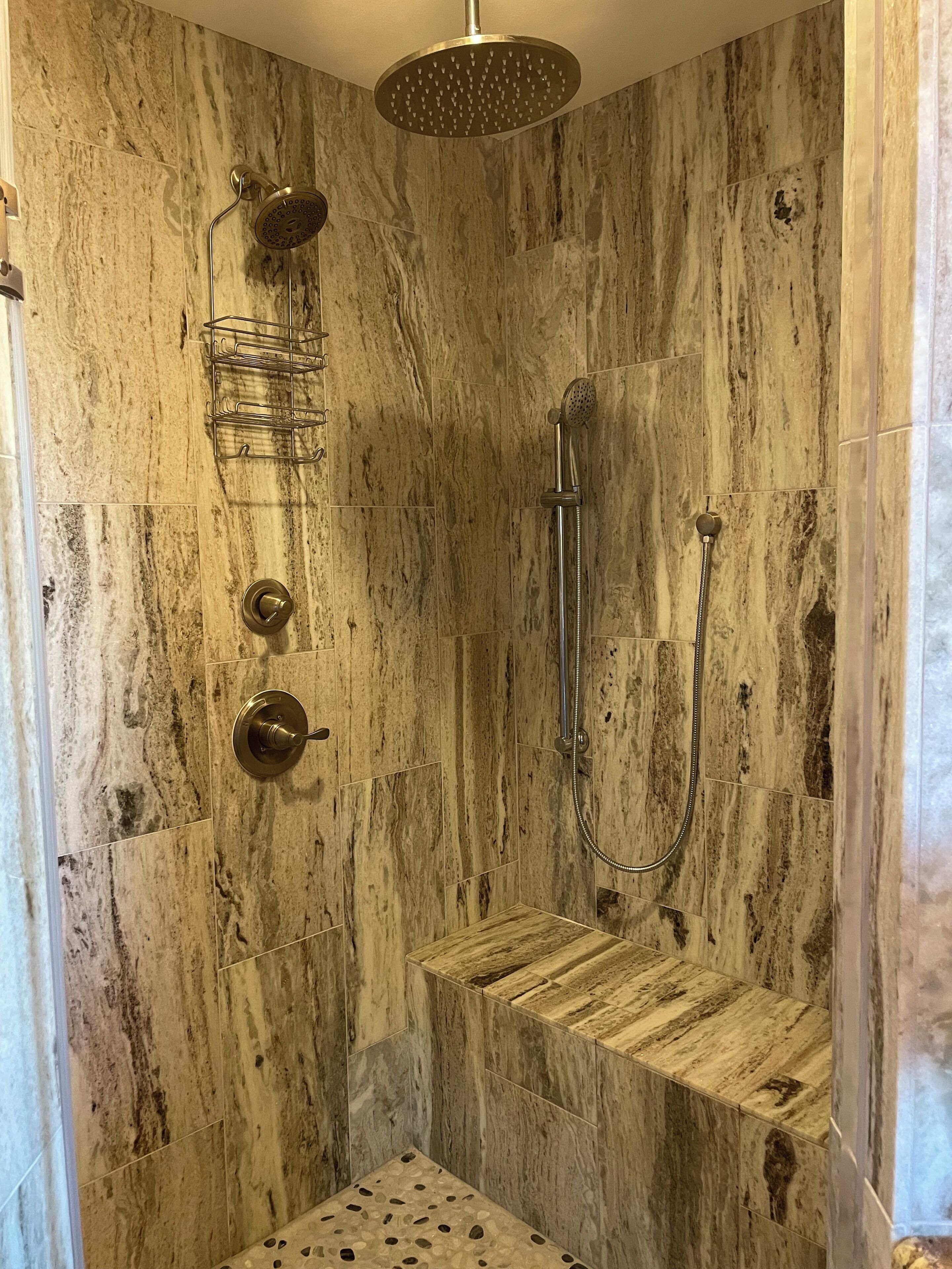 Une douche équipée d’un pommeau de douche à effet pluie, d’un pommeau de douche à main et d’un flexible de douche à main.