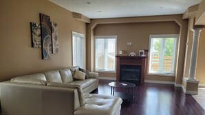 A living room with a beige sectional sofa, a fireplace, and large windows with blinds. - Big house for the big family! 6 bedrooms and 3.5 bathrooms.  (Kitchener)