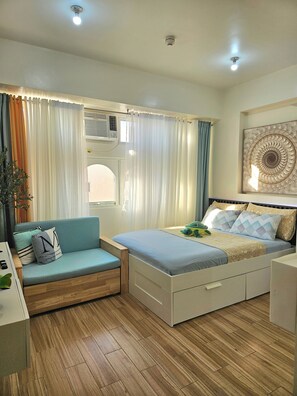 Cozy retreat with a bed, sofa, and seating area, complete with a bedside table and decorative wall piece.