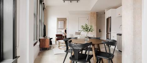 A modern kitchen with a central island, black chairs, and a wooden table.
