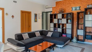 Een moderne woonkamer met een hoekbank, een salontafel en inbouwboekenplanken.