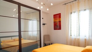 Een hotelkamer met een bed, een stoel, een raam met gordijnen en een schilderij aan de muur.