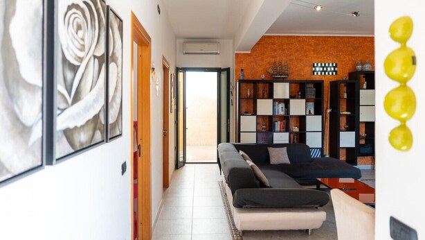 Een moderne woonkamer met een bank, een boekenkast en een groot kunstwerk in een lijst aan de muur.