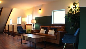 Un salon moderne avec un canapé en cuir marron, un fauteuil bleu et une table basse en bois.