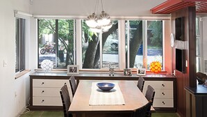A modern kitchen with a large dining table, wooden chairs, and a hanging light fixture. - Cool Mid-Century Modern 3/2 (Austin)