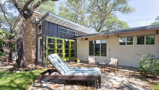 A modern house with a stone patio, a lounge chair, and a dining area. - Cool Mid-Century Modern 3/2 (Austin)