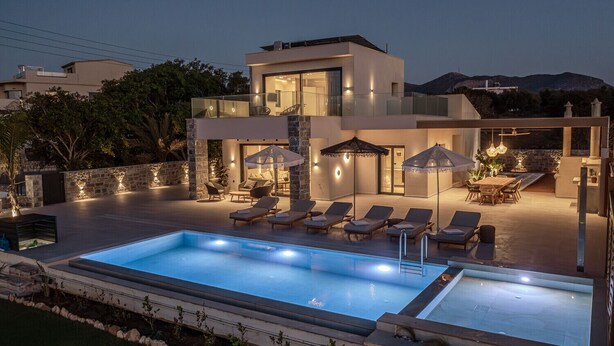 Un espace moderne aménagé au bord de la piscine, avec des chaises longues, des parasols et une piscine.