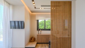 Un intérieur moderne avec un plancher en bois, un banc, un radiateur, une fenêtre donnant sur un espace verdoyant et un paravent décoratif.