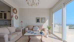 Ein modernes Wohnzimmer mit einer Couch, einem Couchtisch und Blick durch große Schiebeglastüren.