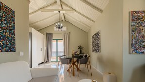 A modern living room with a high ceiling, a dining area, and artwork on the walls. - Gallery Apartment,near beach,shared pool, South Crete (Keratokambos)