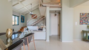 A spacious living area with a staircase, a dining table, and a kitchen in the background. - Gallery Apartment,near beach,shared pool, South Crete (Keratokambos)