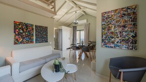 A modern living room with a sofa, coffee table, and a dining area with chairs and a table. - Gallery Villa with Pool, 300m Beach, Sea Views (Keratokambos)