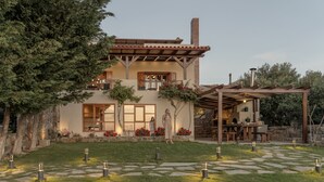 A two-story house with a patio, outdoor seating, and a stone pathway.