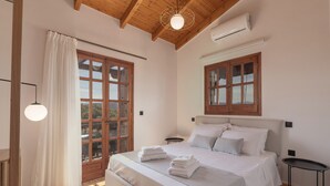 A bedroom with a large bed, wooden beams, a window with curtains, and a bedside table.