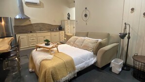 Un dormitorio con cama, mesita de noche, silla y un escritorio pequeño con su silla. Se aprecia un ventilador de techo, un equipo de aire acondicionado y una lámpara fijada a la pared.