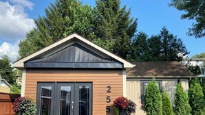 Una casa moderna con techo oscuro, fachada de madera y puerta de garaje.