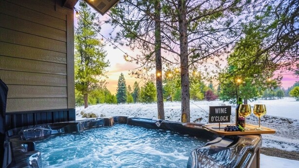 Een jacuzzi met een bord waarop staat 'WINE O'CLOCK' en twee glazen wijn.
