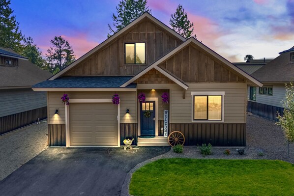 A two-story house with a garage, a front porch with a welcome sign, and a decorative wagon wheel.