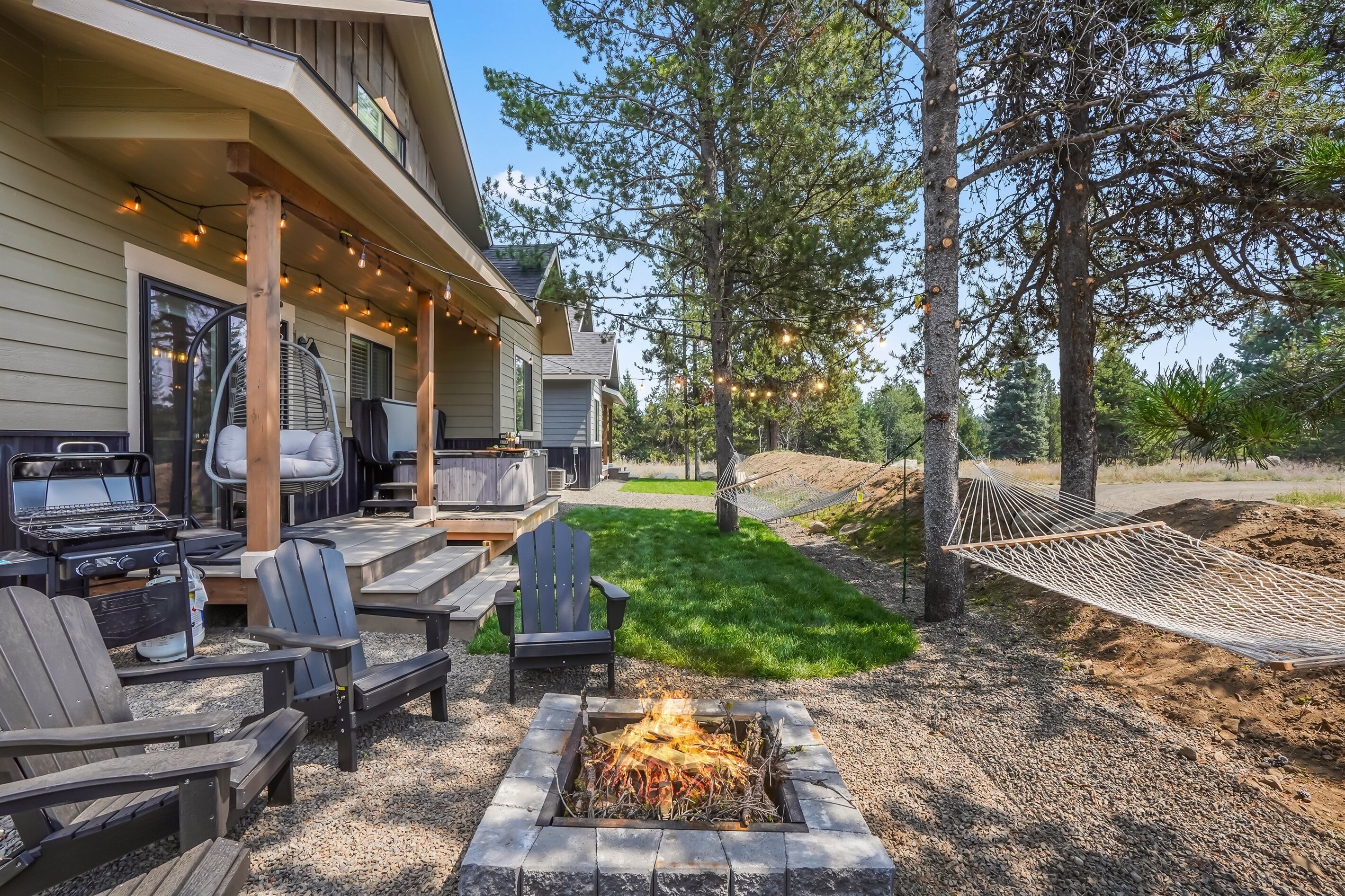 A patio with a fire pit, outdoor seating, and a hammock.