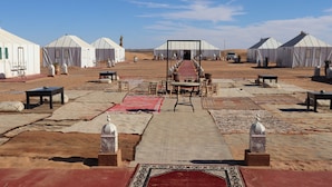 A desert camp with yurts, a central walkway, and outdoor furniture. - Luxury nomadic tented camp  (Merzouga)