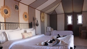 A room with two beds, a large mirror, wall sconces, and a window. - Luxury nomadic tented camp  (Merzouga)