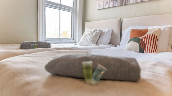 A hotel room with a bed, pillows, and a window.