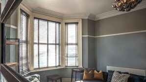 A room with a bay window, a small table, and a sofa with cushions. - Huge House in Derby City Centre | Free Parking (Derby)