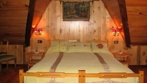 Un dormitorio acogedor tipo cabaña de madera, con una cama, dos mesitas de noche y dos lámparas de pared.