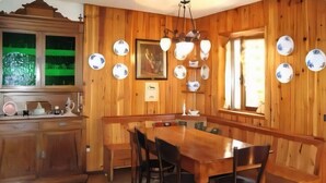 Una habitación con paneles de madera, una mesa de comedor con sillas, una zona de cocina y un ventanal con vistas.