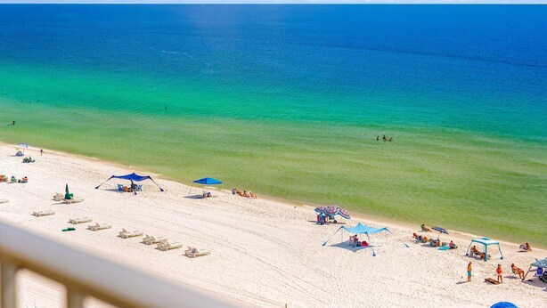 A beach with clear turquoise water, white sand, and several umbrellas and lounge chairs. - NEW! Salt Life at PCB (Panama City Beach)