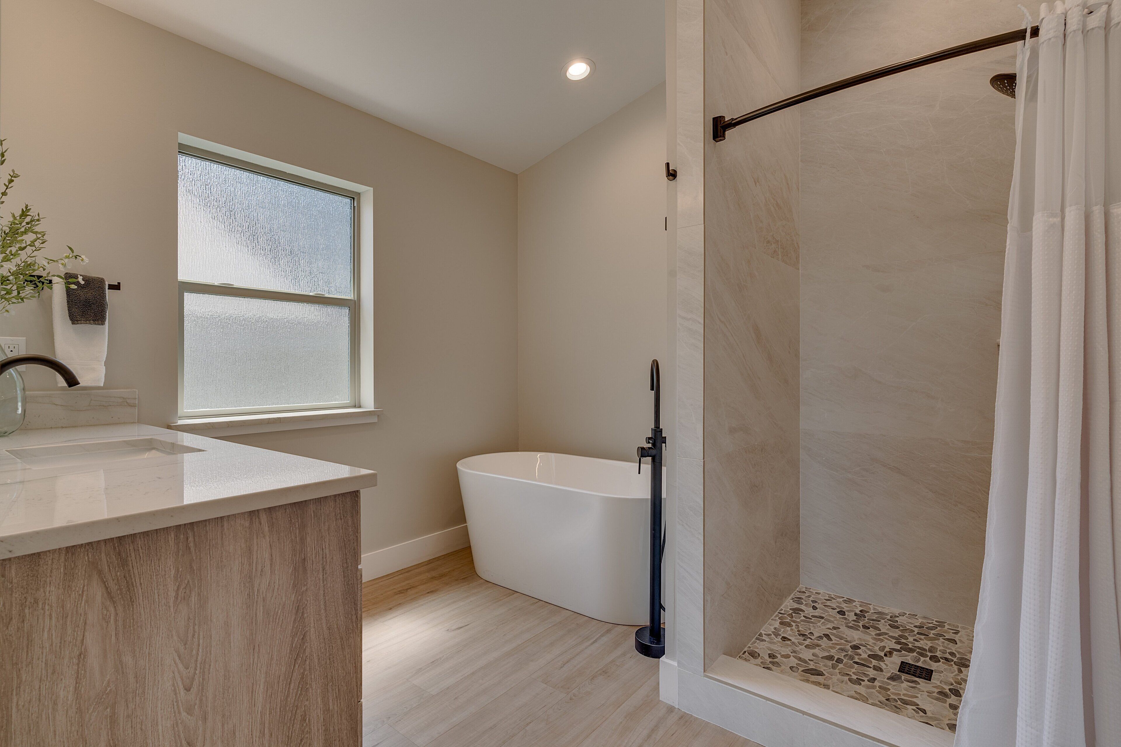 Une salle de bain moderne avec une baignoire sur pieds, un espace douche et une fenêtre laissant entrer la lumière naturelle.