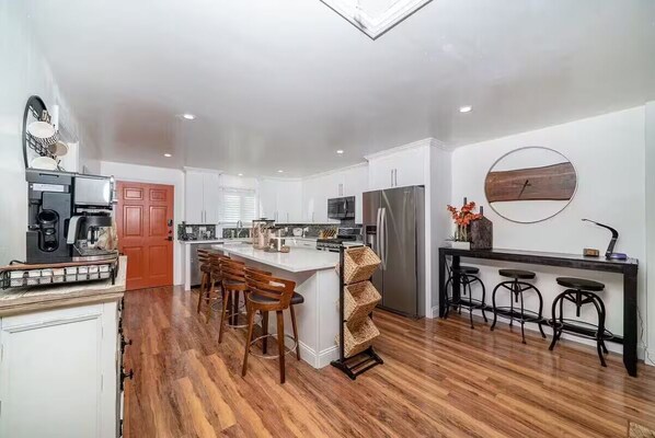 Una cocina moderna con una isla central, taburetes de bar de madera y un reloj de madera redondo en la pared.