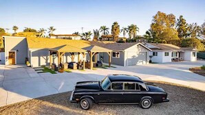 A black vintage car parked in front of a residential area with modern houses and a covered outdoor seating area. - Melrose 2 BR w/ large kitchen + fireplace + patio (Vista)