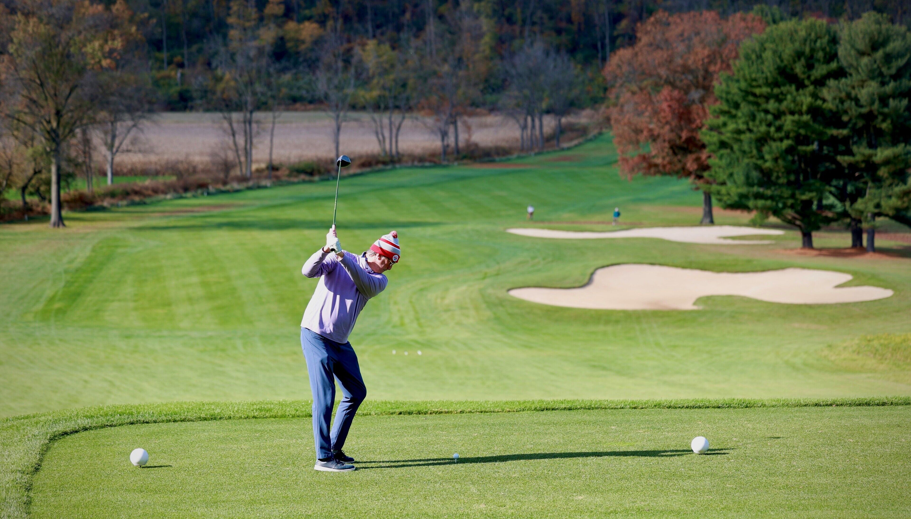A golf course with a putting green, sand bunkers, and trees in the background.