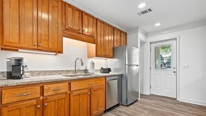 Una cocina con armarios de madera, un refrigerador de acero inoxidable, lavavajillas y encimera de granito.