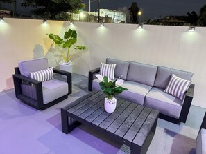Un espace de détente extérieur moderne, comprenant un canapé, deux fauteuils et une table basse.