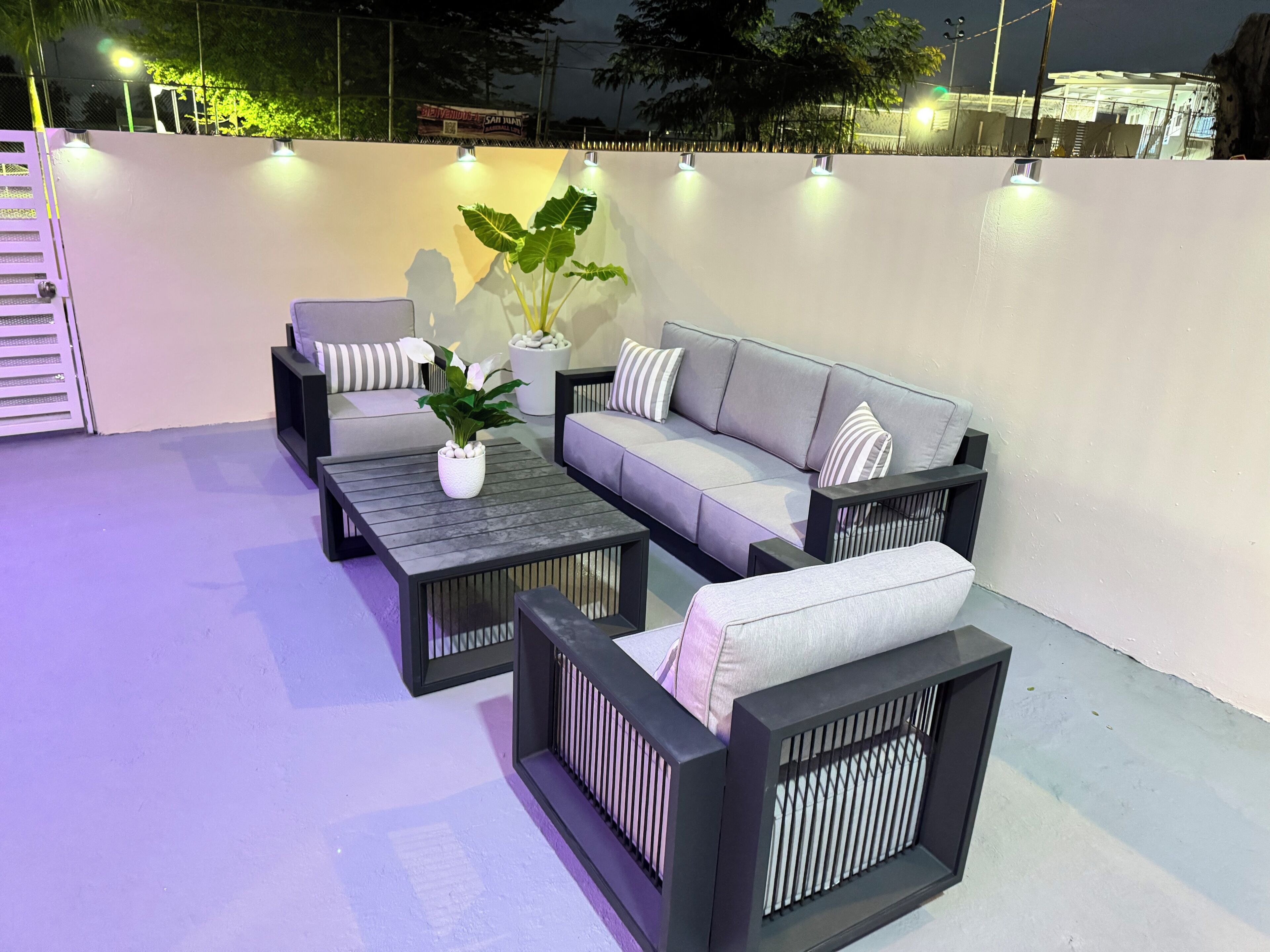 An outdoor seating area with a sofa, two armchairs, a coffee table, and a potted plant.