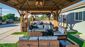 A covered outdoor seating area with wicker furniture and a ceiling fan.