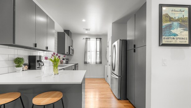 A modern kitchen with a central island, stainless steel appliances, and a framed picture of Barton Springs. - East Austin Condo - 2 Bedrooms & Parking (Austin)