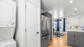 A modern kitchen with a stainless steel refrigerator, a washing machine, and a dryer. - East Austin Condo - 2 Bedrooms & Parking (Austin)