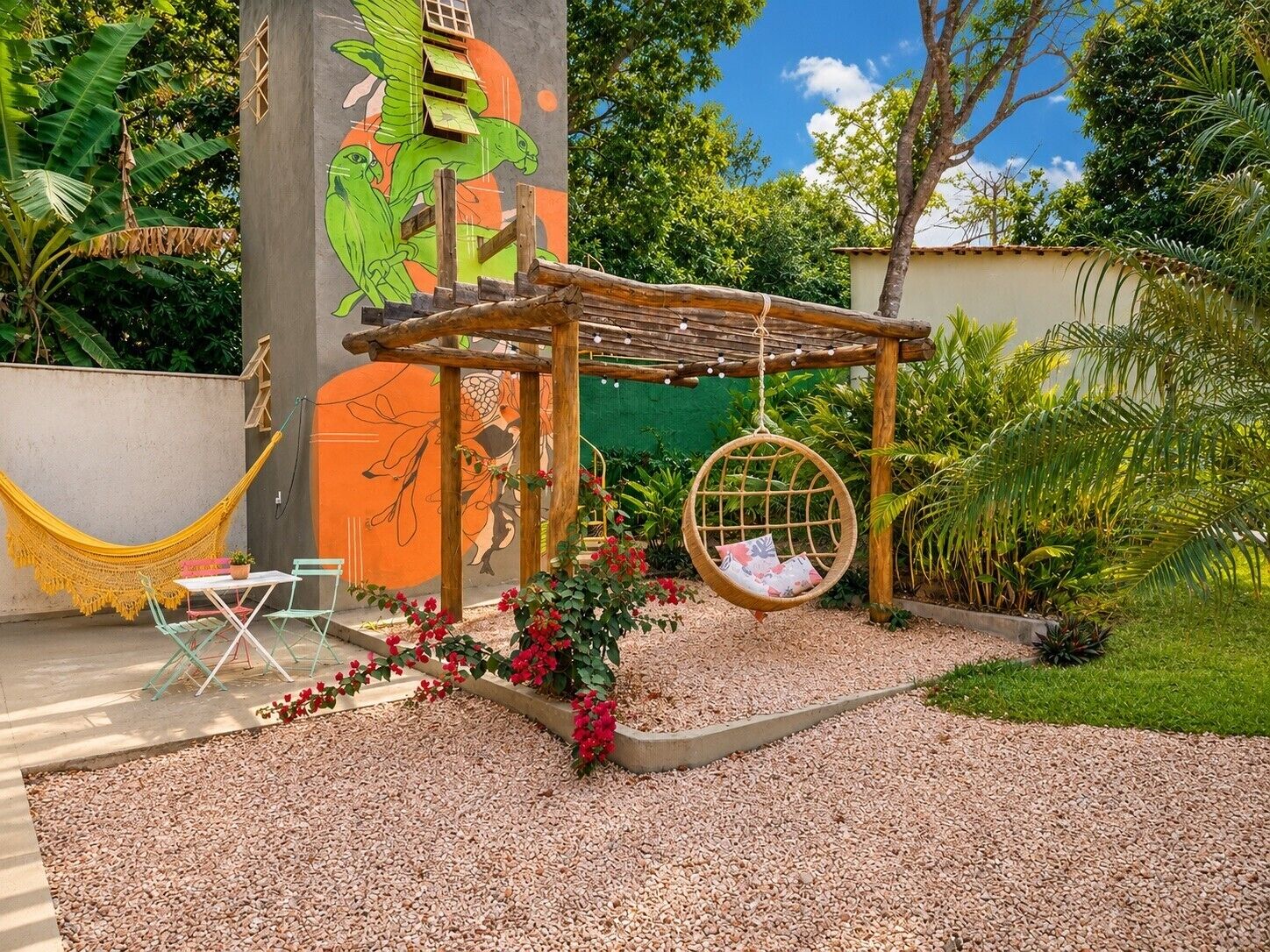 Un jardin avec un hamac, une balançoire et une fresque murale.