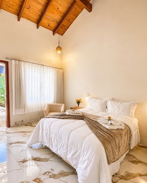Een slaapkamer met een bed, een stoel, een nachtkastje, een raam met gordijnen en een plafondlamp.