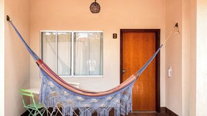 Una hamaca en una habitación con una puerta de madera, una ventana y una silla verde.